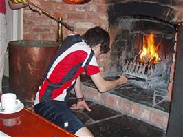 Keir tends the fire while Osian grabs Keir with the fire tongs