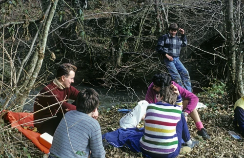 Lunch on the leaf-strewn bank of the River Avon near Lower Reveton, old railway bridge behind. Vicky and Luke among the group.