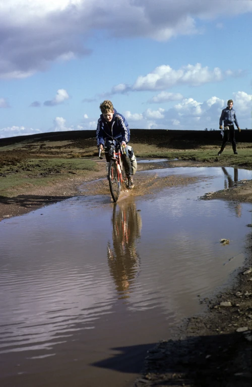 Warren splashes through a flooded stretch near Bicknoller Post, with Jono looking on.