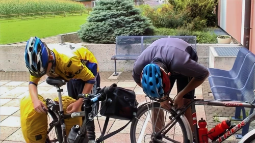 Outside Schaan Youth Hostel: Tao tweaks brakes after hubs and headset; Joe follows suit.