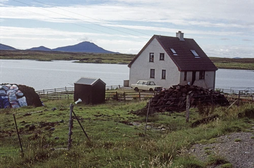 Blathaisbhal resident, two miles from Lochmaddy, stocked with peat bricks for winter. View over Lochmaddy to Eaval (347m).