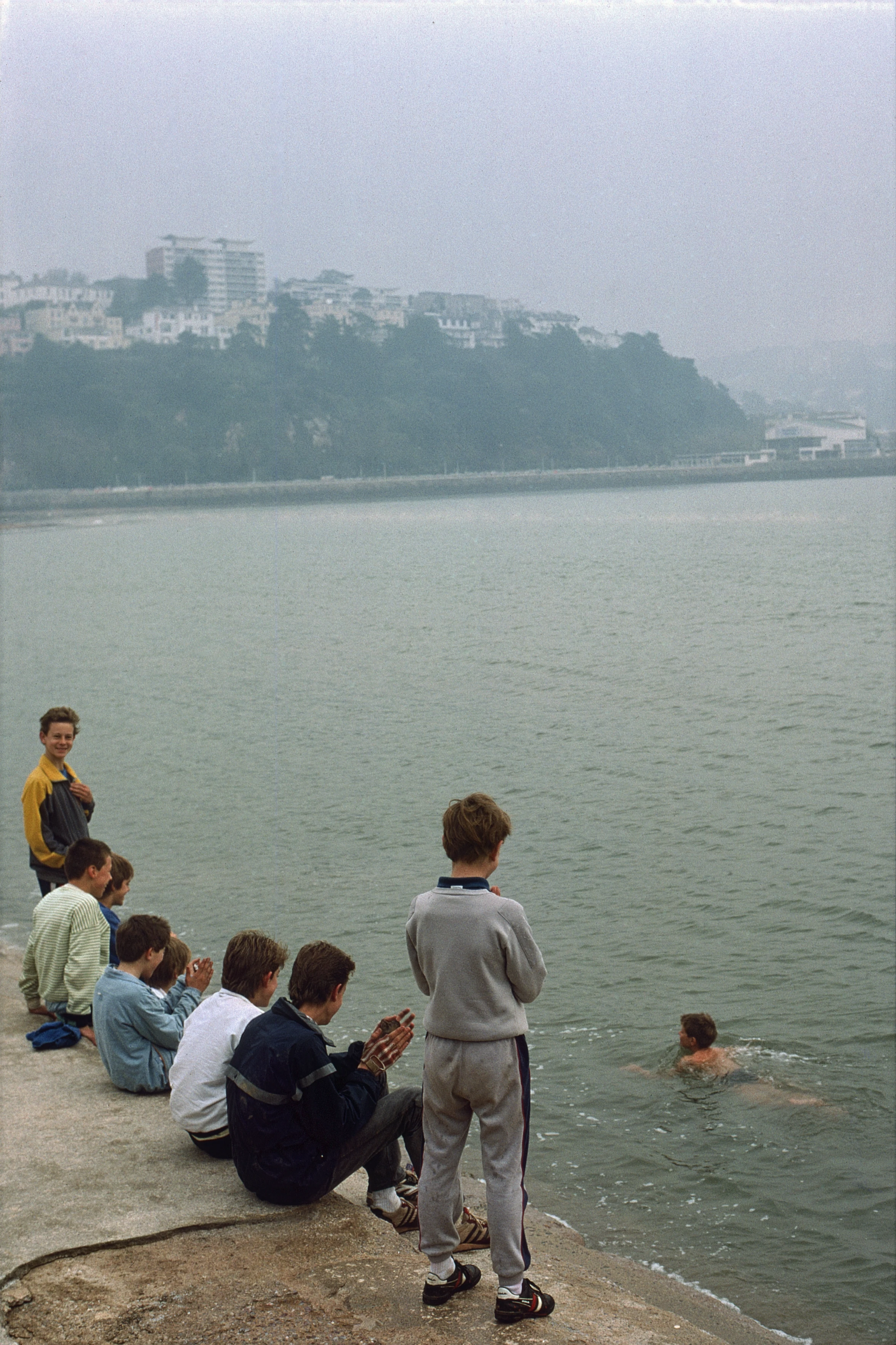 Jonathon Hunt swims in icy water below the Torquay promenade in November, while others watch, amused, from above.
