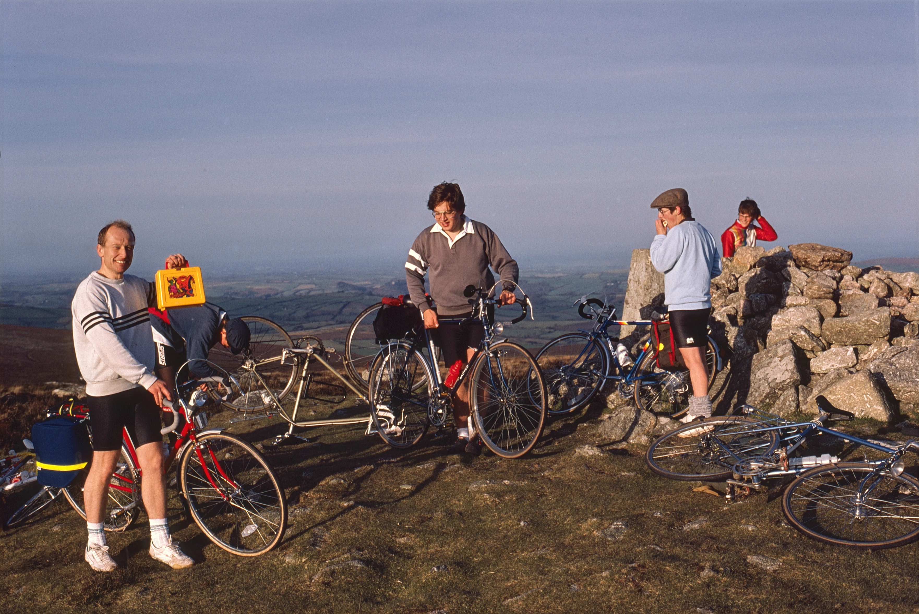 Ken Twydell shows off a Spiderman lunch box atop Hameldown Tor—trig nearby, South Devon views. Simon, Mark, Jenny.