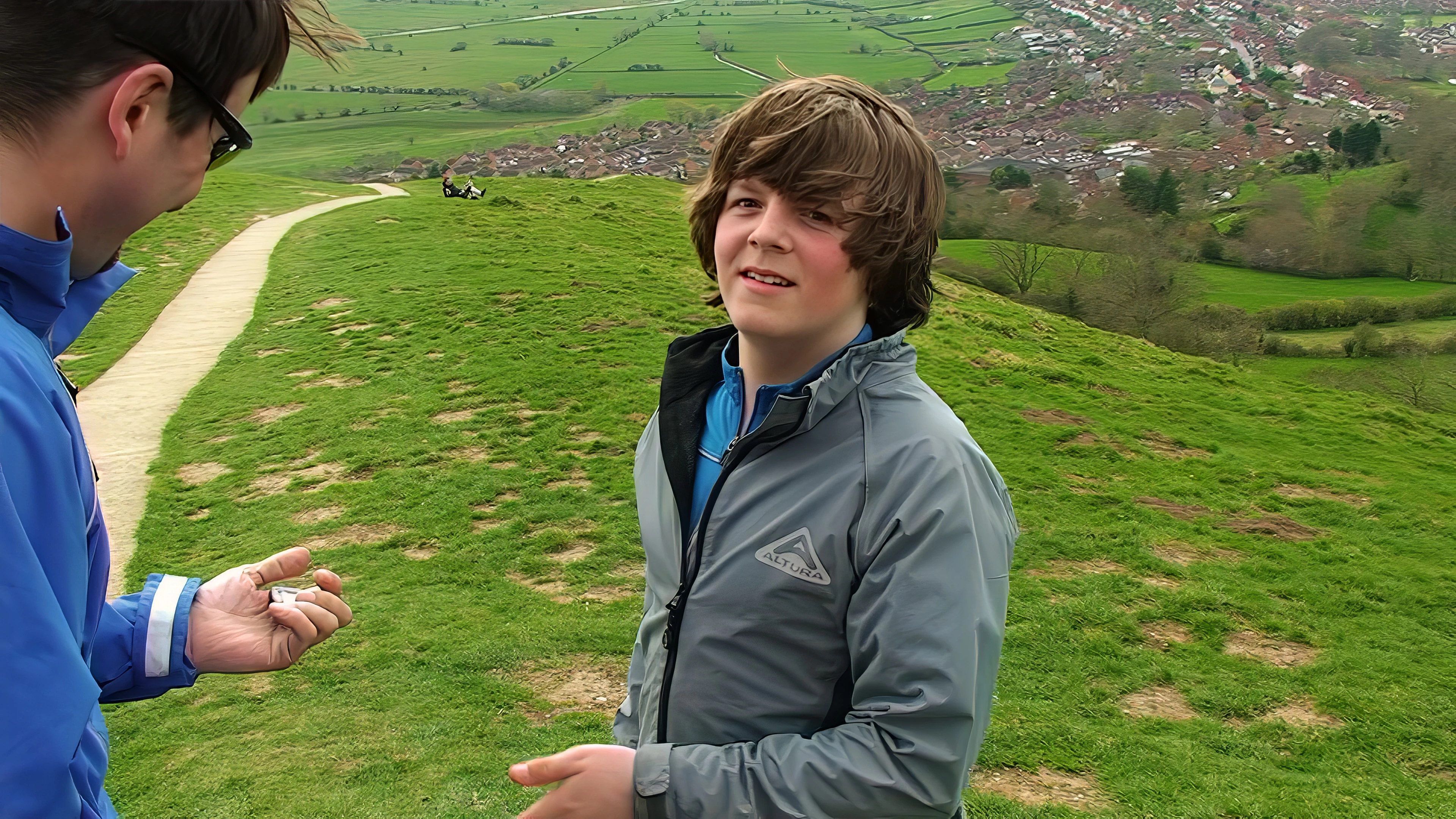 Ash hands his wallet and other valuables to Tao before rolling down Glastonbury Tor